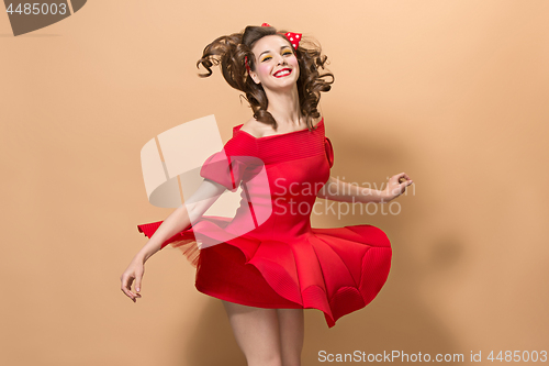 Image of Beautiful young woman with pinup make-up and hairstyle. Studio shot on pastel background