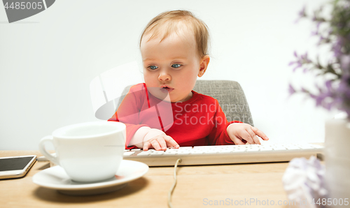 Image of Happy child baby girl toddler sitting with keyboard of computer isolated on a white background