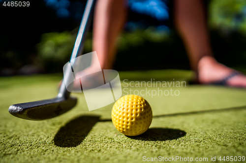 Image of Mini Golf yellow ball with a bat near the hole at sunset