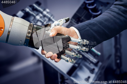 Image of Hand of a businessman shaking hands with a Android robot.