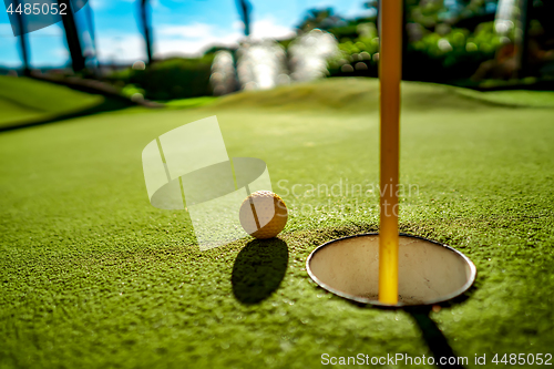 Image of Mini Golf yellow ball on green grass at sunset