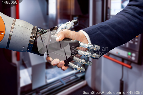 Image of Hand of a businessman shaking hands with a Android robot.