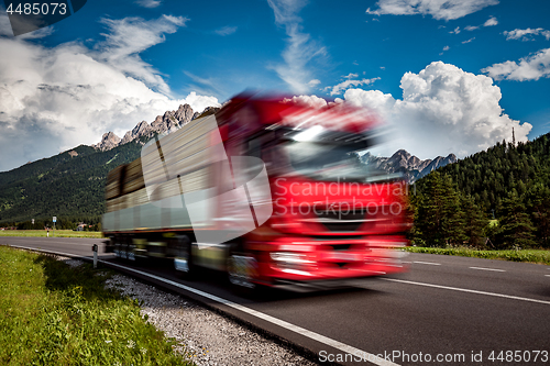 Image of Timber truck rushes down the highway in the background the Alps.