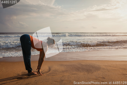 Image of Woman doing yoga Sun salutation Surya Namaskar on beach