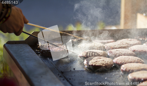 Image of Chef preparing burgers at the barbecue outdoors