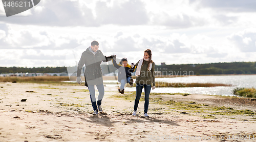 Image of happy family walking along autumn beach