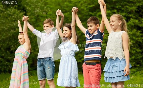 Image of happy kids holding raised hands in summer park