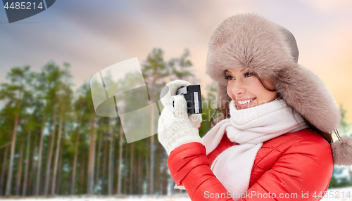 Image of happy woman with film camera over winter forest