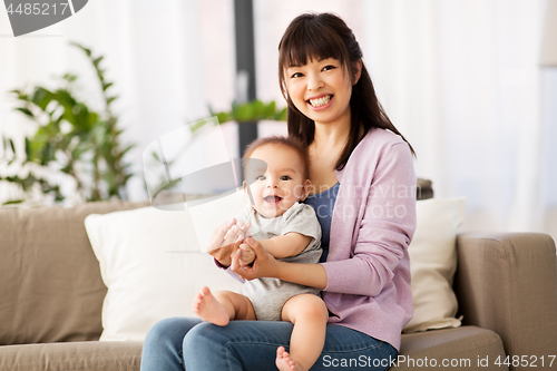 Image of happy young asian mother with little baby at home