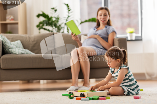 Image of happy baby girl playing with toy blocks at home