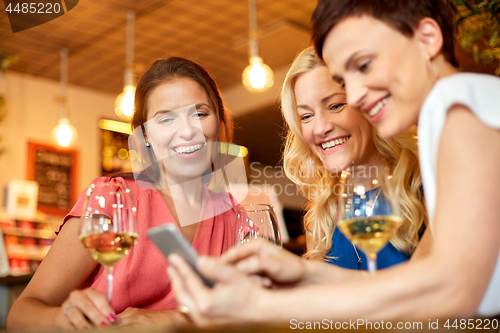 Image of women with smartphone at wine bar or restaurant