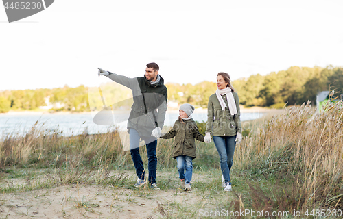 Image of happy family walking along autumn beach