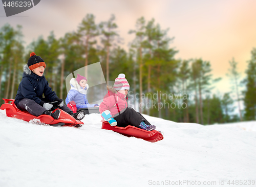 Image of kids sliding on sleds down snow hill in winter