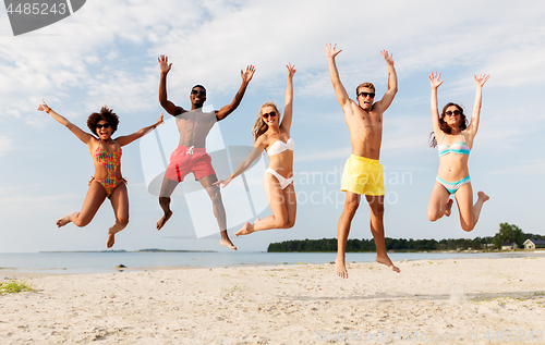 Image of happy friends jumping on summer beach
