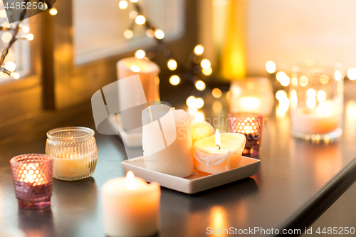 Image of candles burning on window sill with garland lights