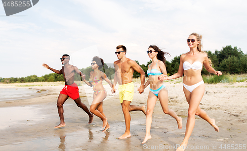 Image of happy friends running on summer beach