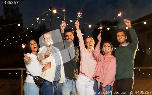 Image of happy friends with sparklers at rooftop party