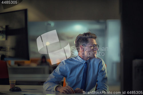 Image of man working on computer in dark office