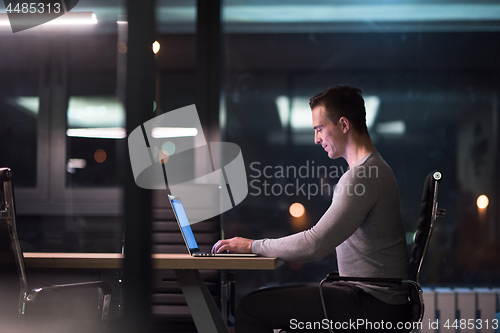 Image of man working on laptop in dark office