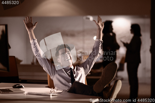 Image of businessman sitting with legs on desk at office