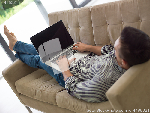 Image of Man using laptop in living room