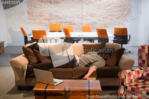 Image of man sleeping on a sofa  in a creative office
