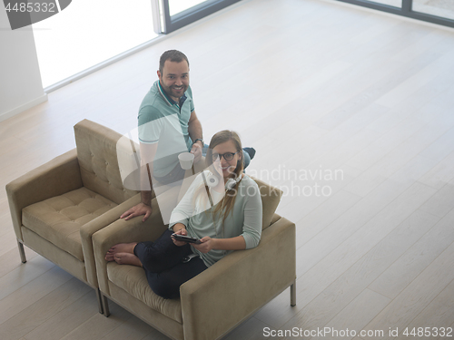 Image of couple relaxing at  home with tablet computers