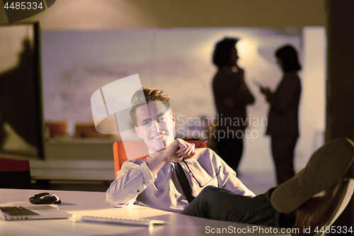 Image of businessman sitting with legs on desk at office