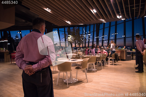 Image of waiter standing with hands behind his back