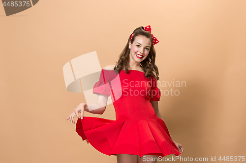 Image of Beautiful young woman with pinup make-up and hairstyle. Studio shot on pastel background