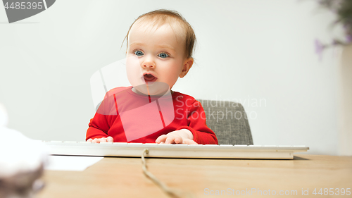 Image of Happy child baby girl toddler sitting with keyboard of computer isolated on a white background