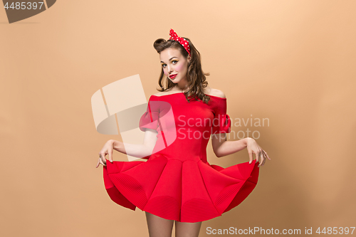 Image of Beautiful young woman with pinup make-up and hairstyle. Studio shot on pastel background