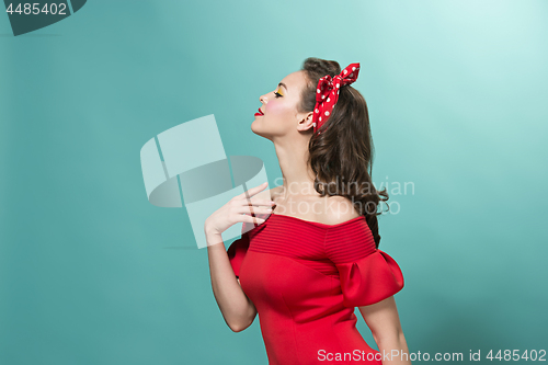 Image of Beautiful young woman with pinup make-up and hairstyle. Studio shot on pastel background