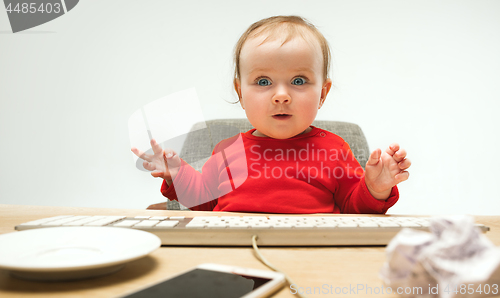 Image of Happy child baby girl toddler sitting with keyboard of computer isolated on a white background
