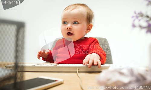 Image of Happy child baby girl toddler sitting with keyboard of computer isolated on a white background