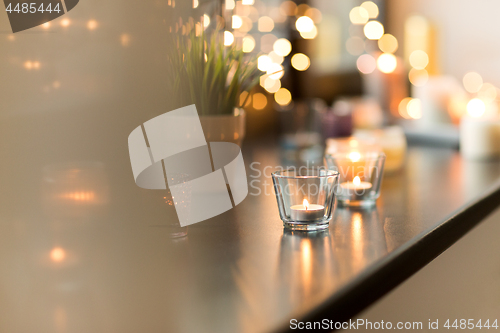 Image of candles burning on window sill with garland lights