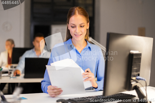 Image of businesswoman with papers working at night office