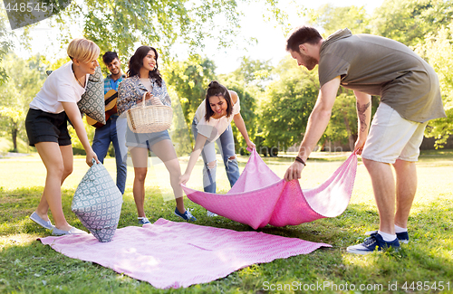 Image of friends arranging place for picnic at summer park