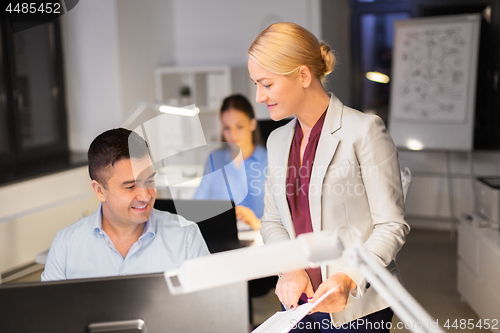 Image of business team with papers working late at office