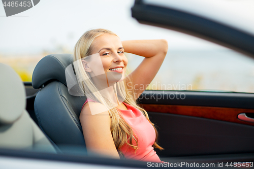 Image of happy young woman driving convertible car