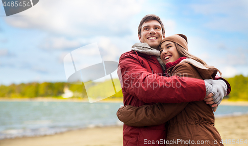 Image of happy young couple hugging over autumn beach