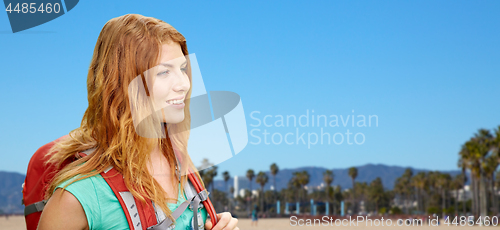 Image of smiling woman with backpack over venice beach