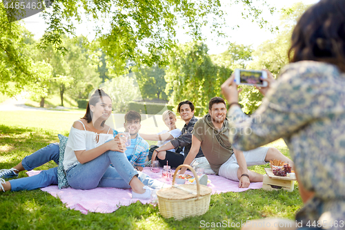 Image of friends photographing by smartphone at picnic