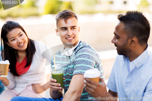 Image of friends drinking coffee and juice talking in city