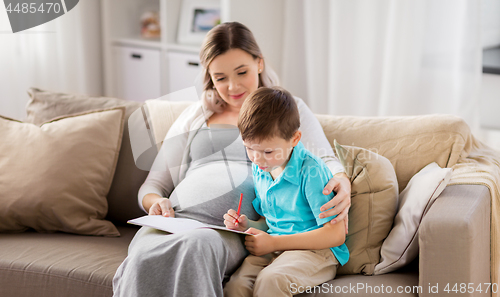 Image of pregnant mother and son with workbook at home