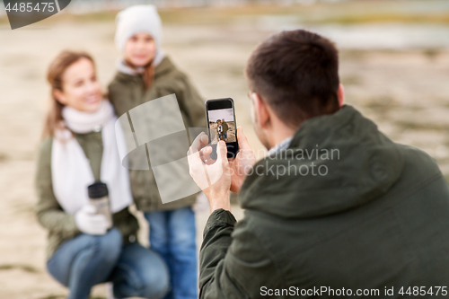 Image of family photographing by smartphone on autumn beach