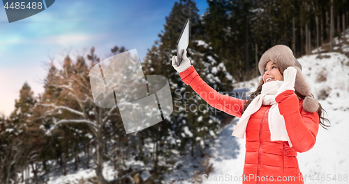 Image of woman in winter fur hat with tablet pc outdoors