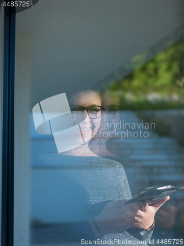 Image of Woman using tablet at home by the window
