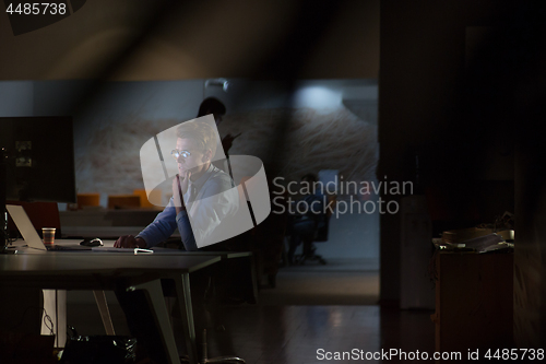 Image of man working on computer in dark office