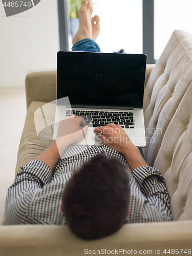 Image of Man using laptop in living room